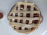 Fototapeta Uliczki - A raw strawberry rhubarb pie with the traditional lattice pastry pattern. Ready to bake on the countertop with some mini ones beside it