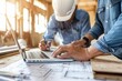 A closeup of two people, one wearing a blue shirt and the other in a white helmet with a laptop on a table looking at construction plans while holding a pencil and paper Generative AI