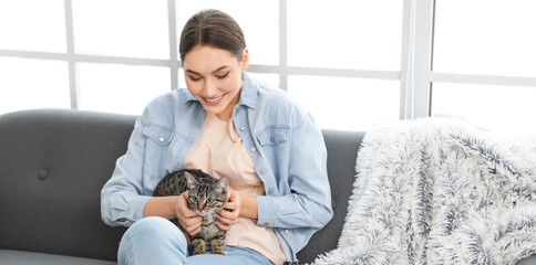 Wall Mural - Beautiful young woman with cute cat at home