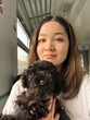 Pretty Asian girl holding black poodle puppy in arms while sitting inside train. Korean female person traveling with dog. Woman hugging puppy. Soft focus. film grain pixel texture. Defocused.