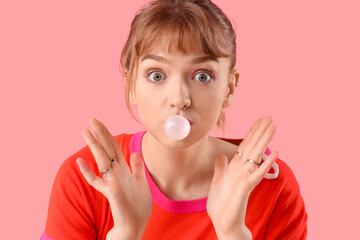 Canvas Print - Shocked young woman with chewing gum on pink background, closeup