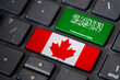 Canada and Saudi Arab flags on computer keyboard