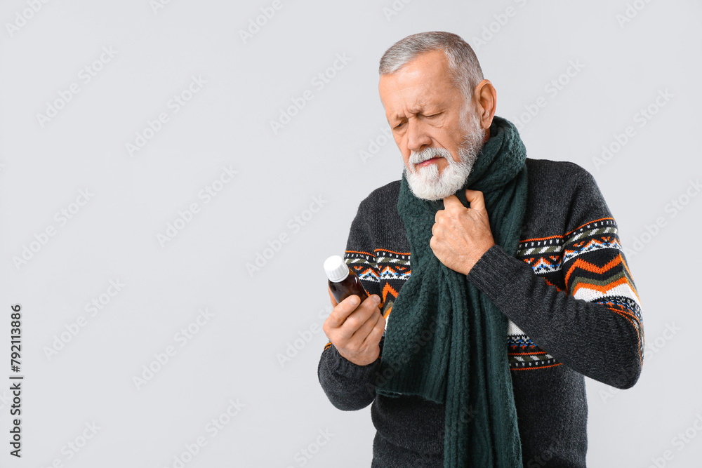 Old man with sore throat holding cough syrup on white background