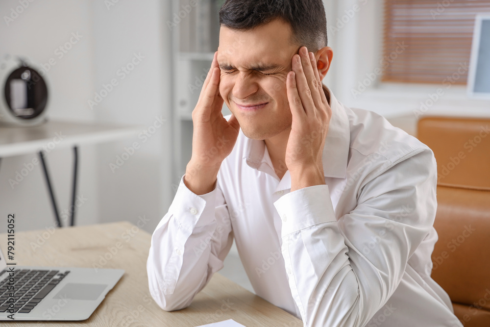 Young businessman suffering from migraine in office
