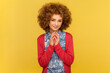 Portrait of devious cunning woman with Afro hairstyle clasping hands and smirking mysteriously, scheming cheats, evil prank. Indoor studio shot isolated on yellow background.
