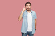 Portrait of intelligent bearded man in blue casual style shirt standing raises fore finger as receives good idea, looking at camera. Indoor studio shot isolated on pink background.