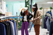 African american couple trying on hat and having fun in shopping mall. Carefree man and woman friends checking out and wearing accessories while dancing in clothing store