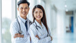 © Luxetify - Two young Asian doctor couples are facing the camera smiling happily, wearing full uniforms standing in the clinic corridor