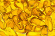 Omega 3 krill fish oil capsules supplements scattered health yellow gold backlit.