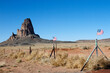 An impressive rock formation and two American flags along a rural road in Arizona
