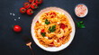 Cooked spaghetti pasta with big shrimp and tomato sauce, black table background, top view