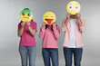 © New Africa - People covering faces with emoticons on grey background