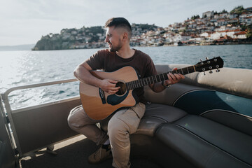 Poster - Casual guitarist smiles as he enjoys music on a sunny day with the ocean and cityscape behind him.