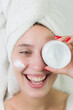 Happy young woman applying serum on her face