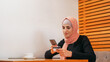 Online shopping. Mobile banking. Beautiful woman in hijab ordering buy on phone with credit card payment internet purchase at cafe copy space.