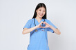 Smiling young woman doctor makes a heart shape with her hand isolate on white background.