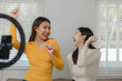 Two beautiful Asian women are using electronic devices to entertain themselves as a group activity which is dancing in their apartment, Spend free time together happily at home during the weekends.