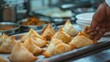 Chef handcrafting delectable samosas, their golden crusts glistening with savory filling peeking through.