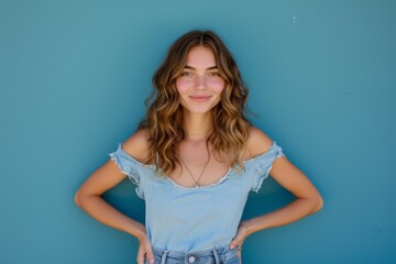 Wall Mural - Smiling Caucasian woman posing with hands on hips isolated on blue background