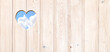 Heart-shaped hole in wooden boards and blue sky with clouds. Heart shape hole in wood fence. Go green. Ecology, global ecological resource, eco and zero waste concept. Copy space for text