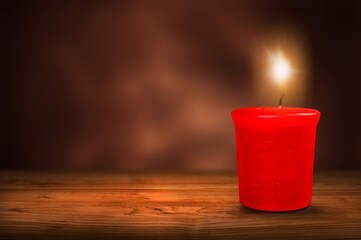 Poster - A lit candle with bright flame on dark background