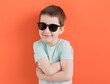 Caucasian boy in sunglasses orange background