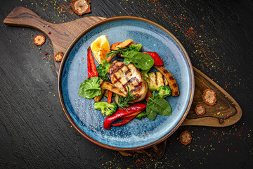 Wall Mural - Sturgeon steak with roasted vegetables. Menu for a pub on a dark background. Colorful juicy food photography.