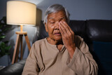 Fototapeta Lawenda - senior woman with eye fatigue while sitting on sofa in the living room at night