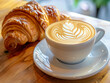 The coffee is served in a white porcelain cup and the croissant is golden brown on the outside and soft and buttery on the inside.