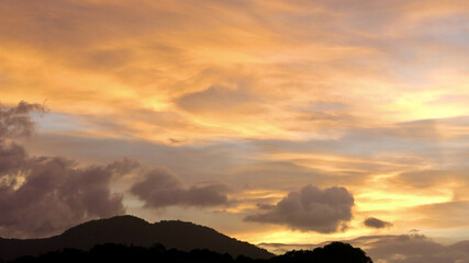 Wall Mural - Sunset over a tropical island. View of the silhouette of a tropical island and clouds colored by the rays of the setting sun.