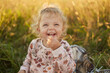 Happy Caucasian little girl laughing in the summer outdoors having picnic eating fruits expressing happiness having fun on sunny summer day biting grapes on bright sunset