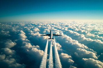 Wall Mural - Plane is flying through cloudy sky and leaving contrails behind it.