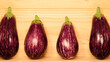 Beautiful several eggplants laid out in a row on a wood surface