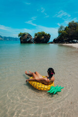 Wall Mural - Woman in a yellow inner tube at the beach by the sea