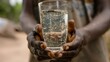 Closeup of a person holding a glass of clean drinkable water emphasizing the stark difference in access to water between different communities. .