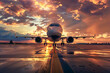 A large white airplane is parked on a runway at sunset. The sky is filled with clouds, creating a moody atmosphere