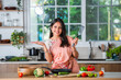 Hppy young asian indian woman in kitchen promoting utensils and ok sign