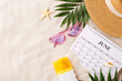 Summer vacation setup, top view of beach gear and calendar on sand texture with space for text
