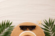 Flat lay photo of stylish straw hat with sunglasses, tropical leaves and starfish, arranged on sandy background with space for ad