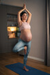 A full length shot of a beautiful pregnant woman practicing yoga at home