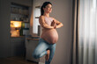 A relaxed pregnant woman doing yoga at home and balancing her weight on one leg