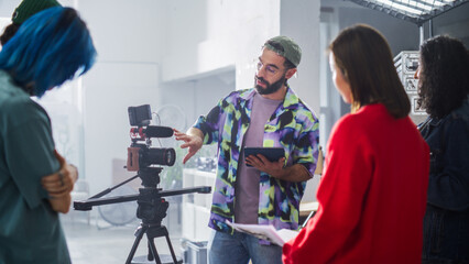 Young Diverse Team Collaborates On A Film Set, With A Male Latin Director Guiding The Shoot, Surrounded By A Camera And Crew In A Brightly Lit Studio, Focusing On Teamwork And Creativity.