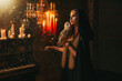 Art Photo real fantasy gothic woman holding white barn owl birds tamed pet. Fantasy lady Elf Blonde hair sexy girl with wild bird. dark room black dress cape hood candles burning light classic piano