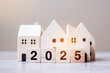 2025 Happy New Year with house model on table wooden background. Banking, real estate, investment, financial, savings and New Year Resolution concepts