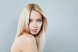 Fototapeta  - Smiling young blonde lady with fresh clear skin and long smooth straight hairstile on white background