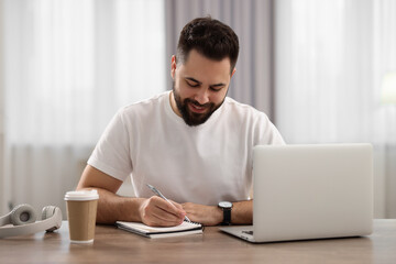 Sticker - Young man writing down notes during webinar at table in room