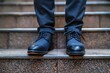 A low angle view focusing on the feet of a businessman wearing formal shoes ascending a modern staircase