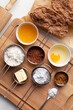 Gingerbread dough for Christmas and ingredients for making dough - egg, honey, spice, powdered sugar, butter, cacao, flour, baking soda on a wooden background. Top view