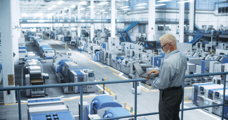 Leinwandbilder - Experienced Male Engineer Standing on a Platform, Using Laptop Computer and Overlooking Production at a Modern Automated Electronics Manufacture with AI Support. Factory Executive at Work