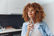 © SHOTPRIME STUDIO - Attractive African American woman with glass of water standing in modern kitchen at home, healthy lifestyle concept